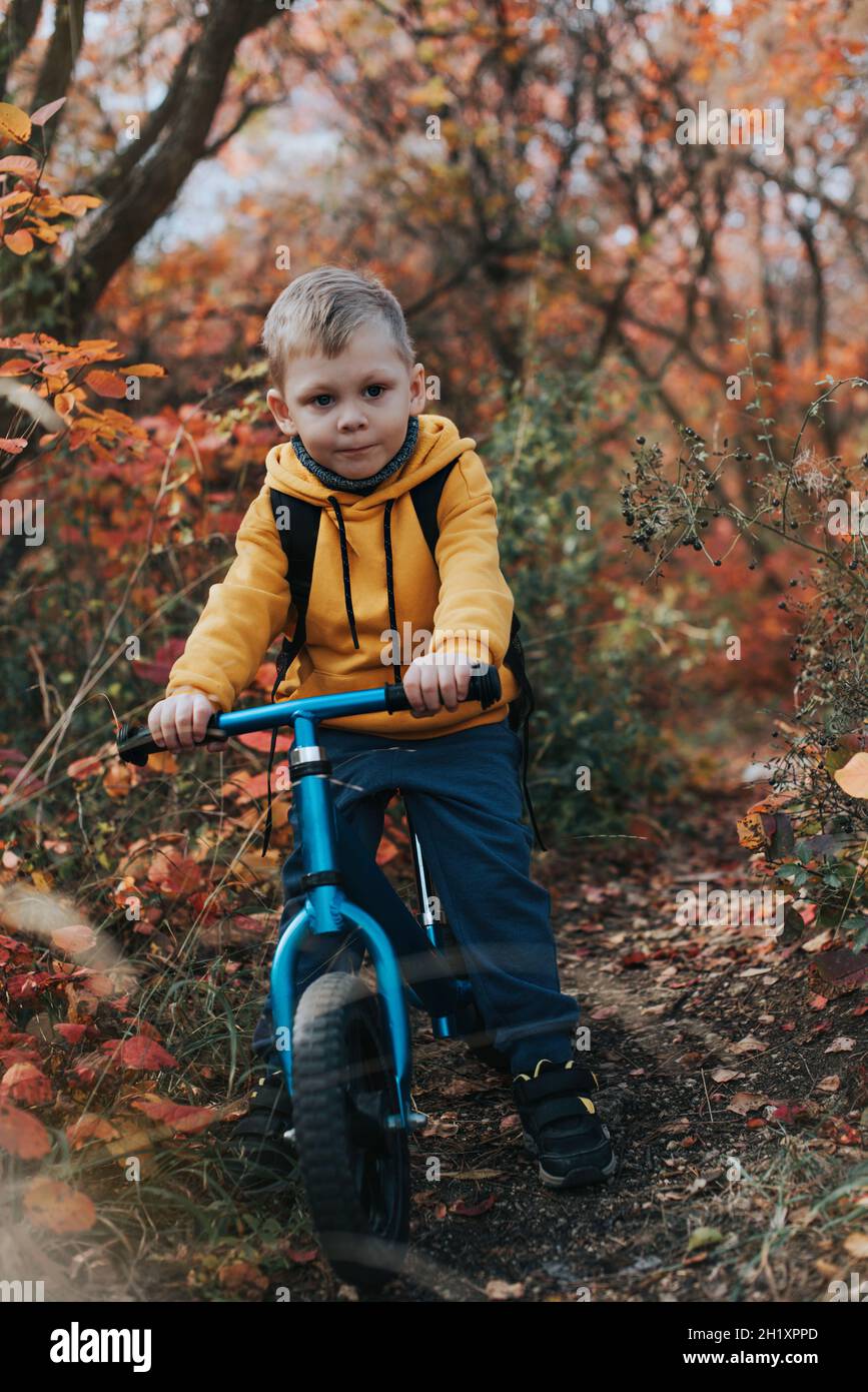 Boy on a balance bike ride in the autumn forest Stock Photo