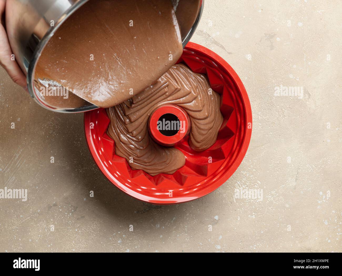 pouring chocolate cake dough in silicone baking form, top view. process