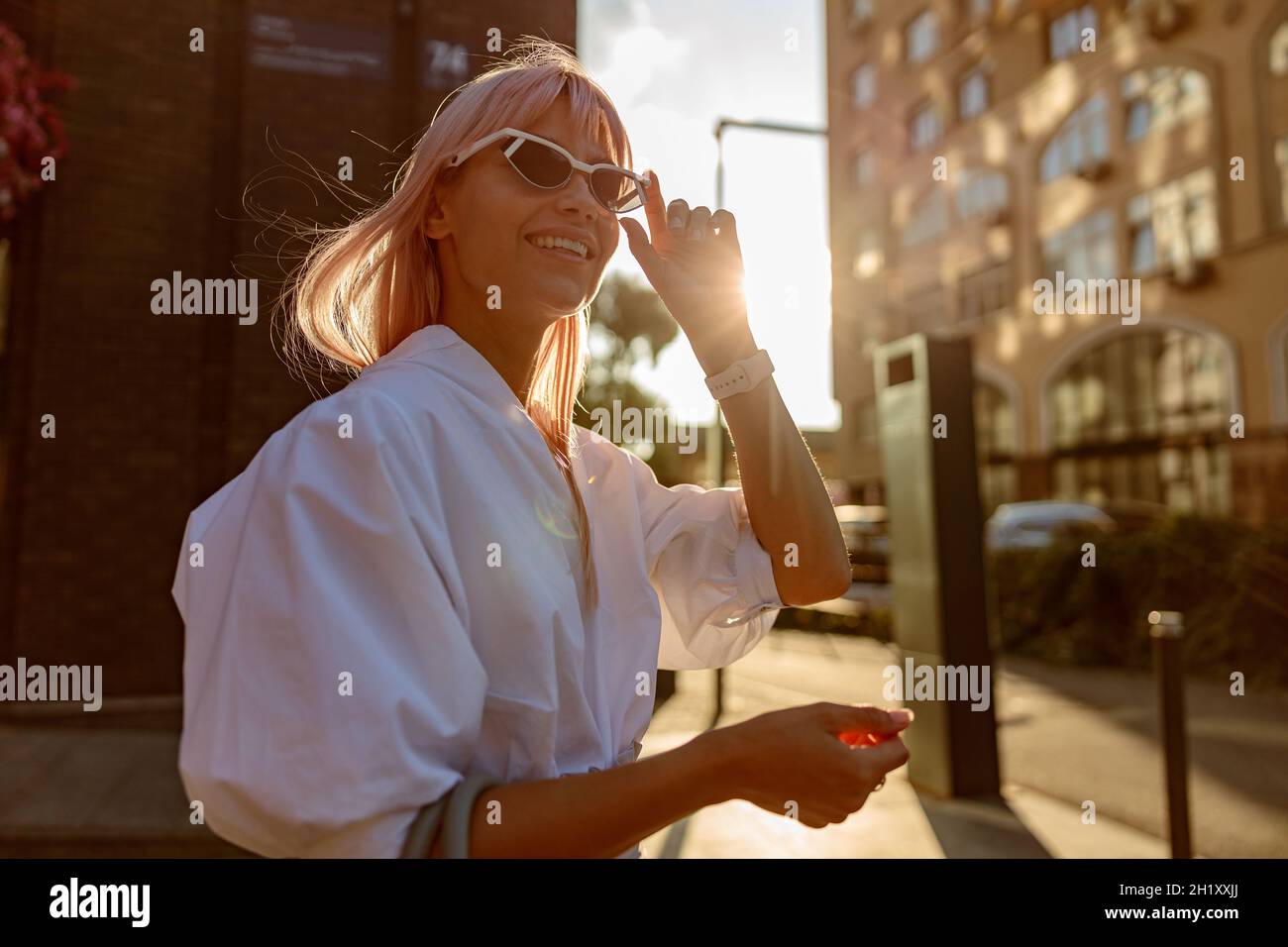 Joyful young woman in sunglasses standing on the street Stock Photo