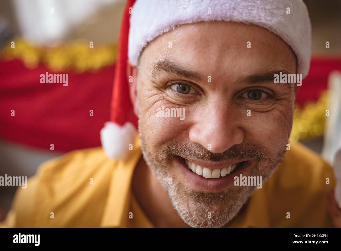 Portrait of caucasian man wearing santa hat smiling at home during christmas Stock Photo