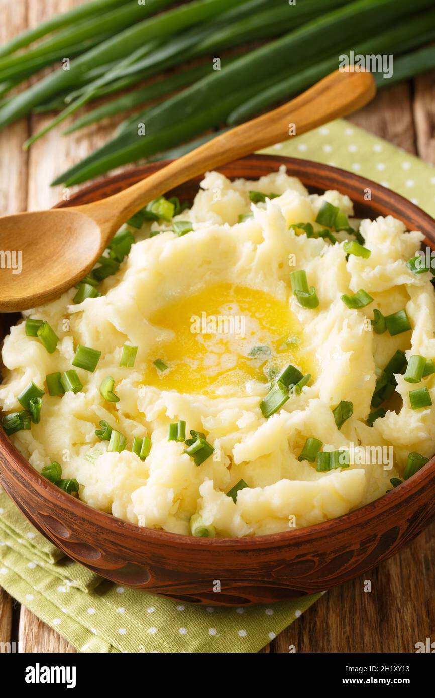 Champ is an Irish dish of mashed potatoes with scallions, butter, and milk close up in the bowl on the table. Vertical Stock Photo