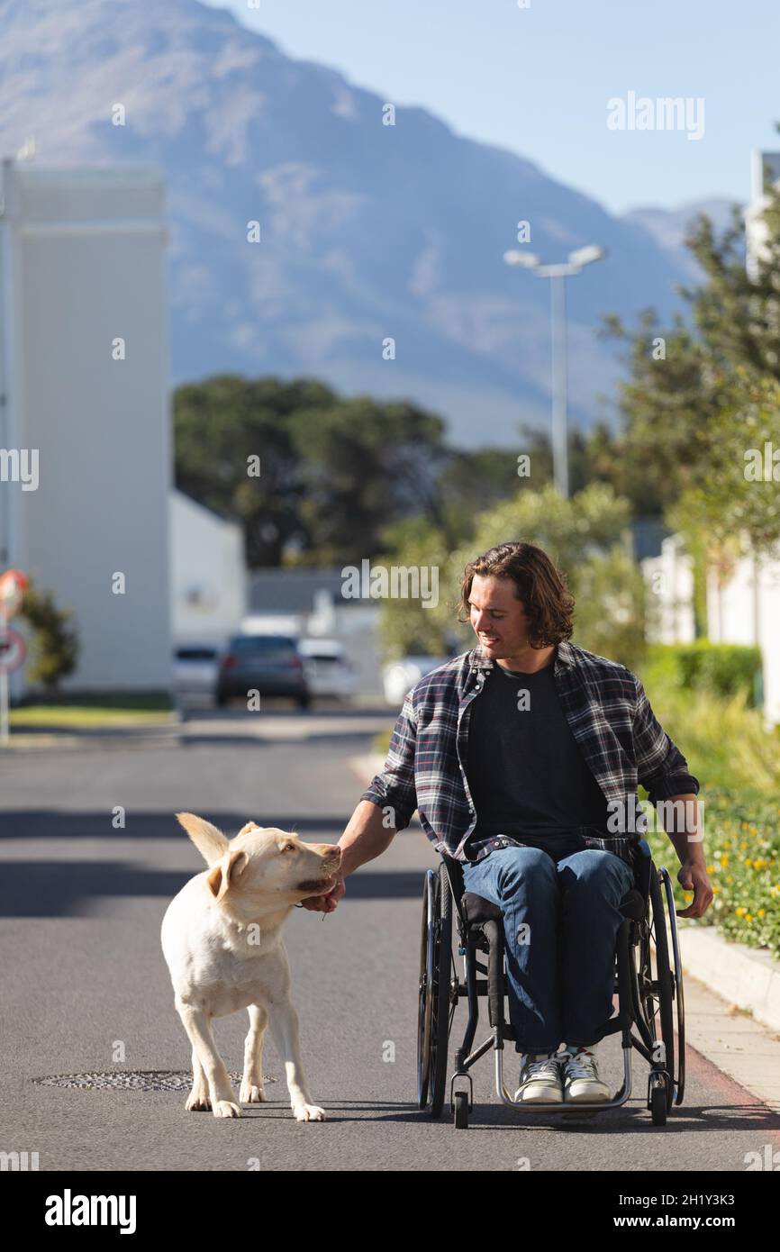 Caucasian disabled man with dog sitting on wheelchair on the road Stock Photo
