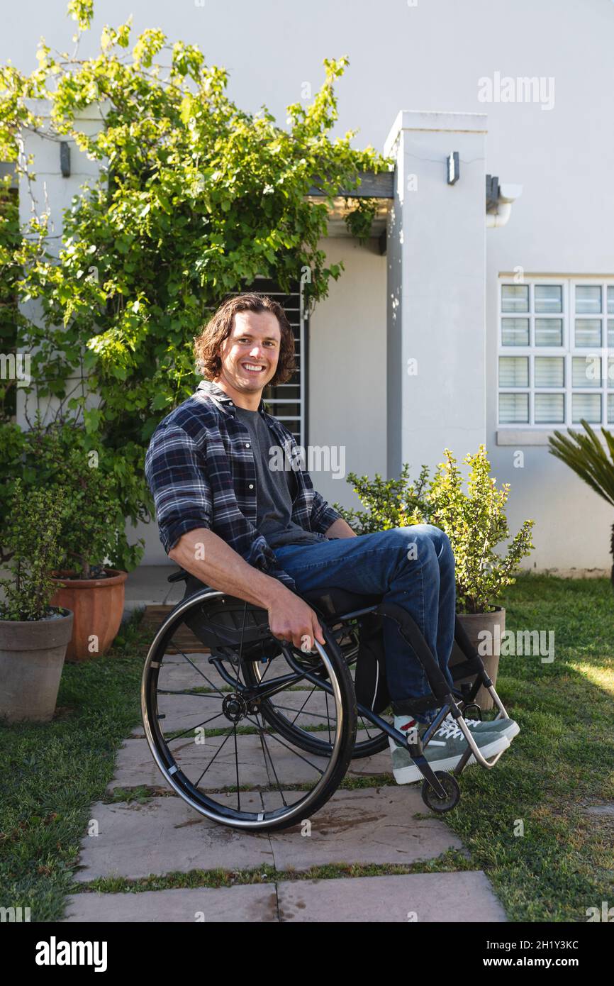 Portrait of caucasian disabled man sitting on wheelchair smiling in the garden Stock Photo