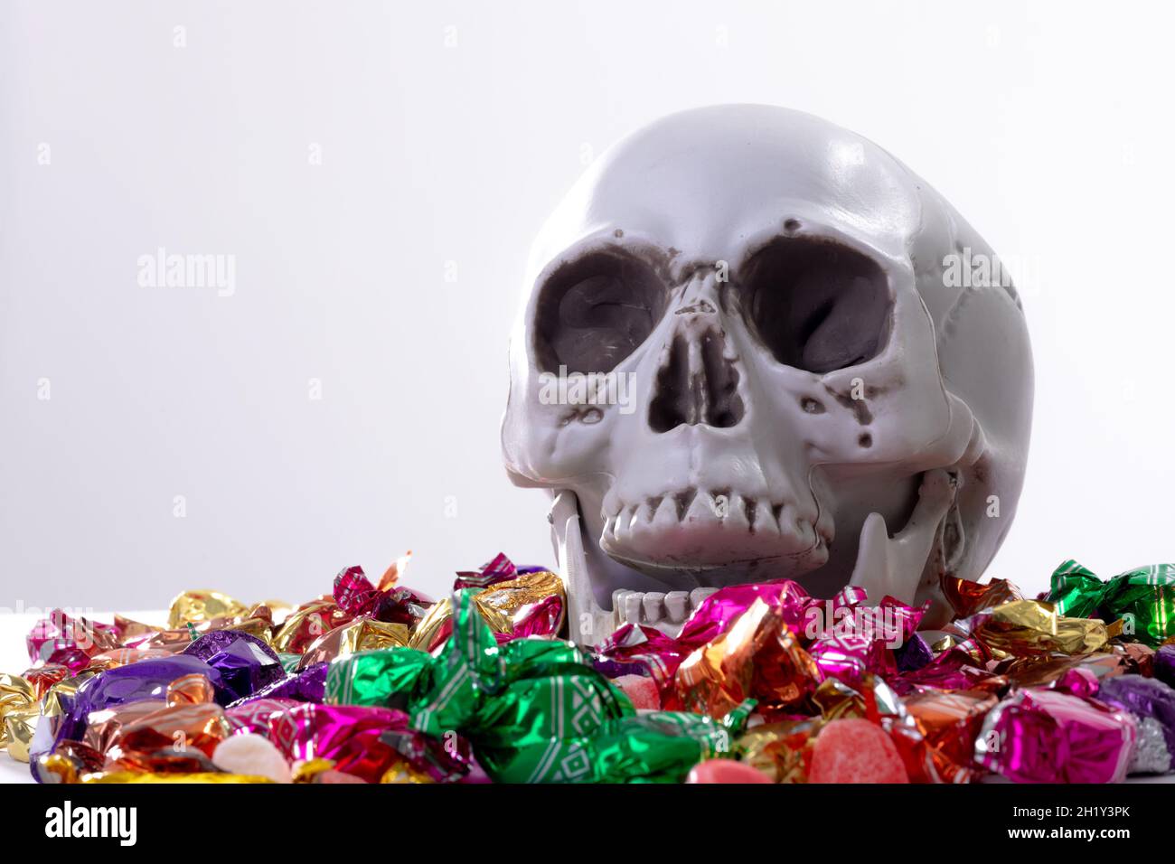 Composition of halloween laughing skull with trick or treat sweets on white background Stock Photo