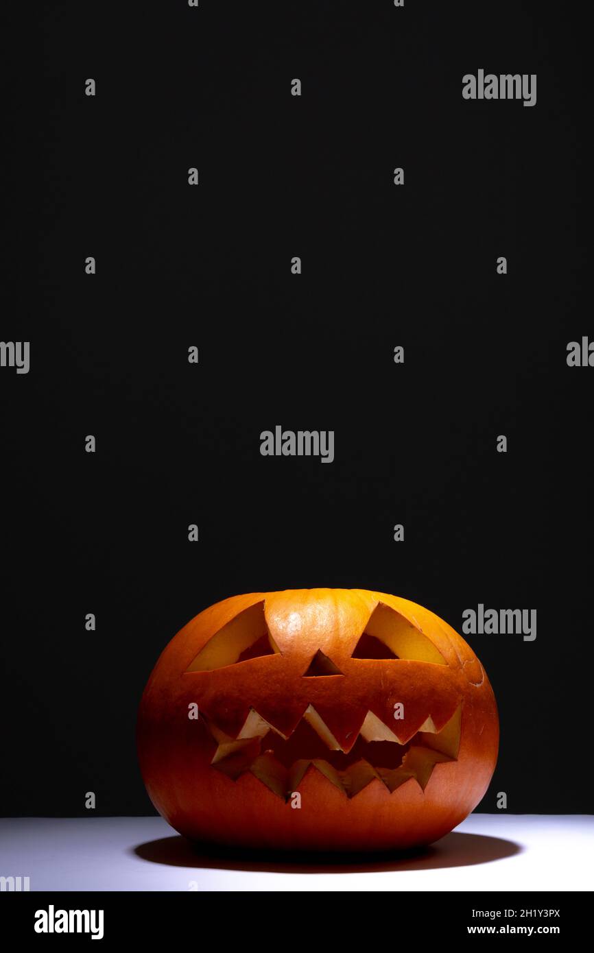 Composition of scary halloween carved orange pumpkin on black ...
