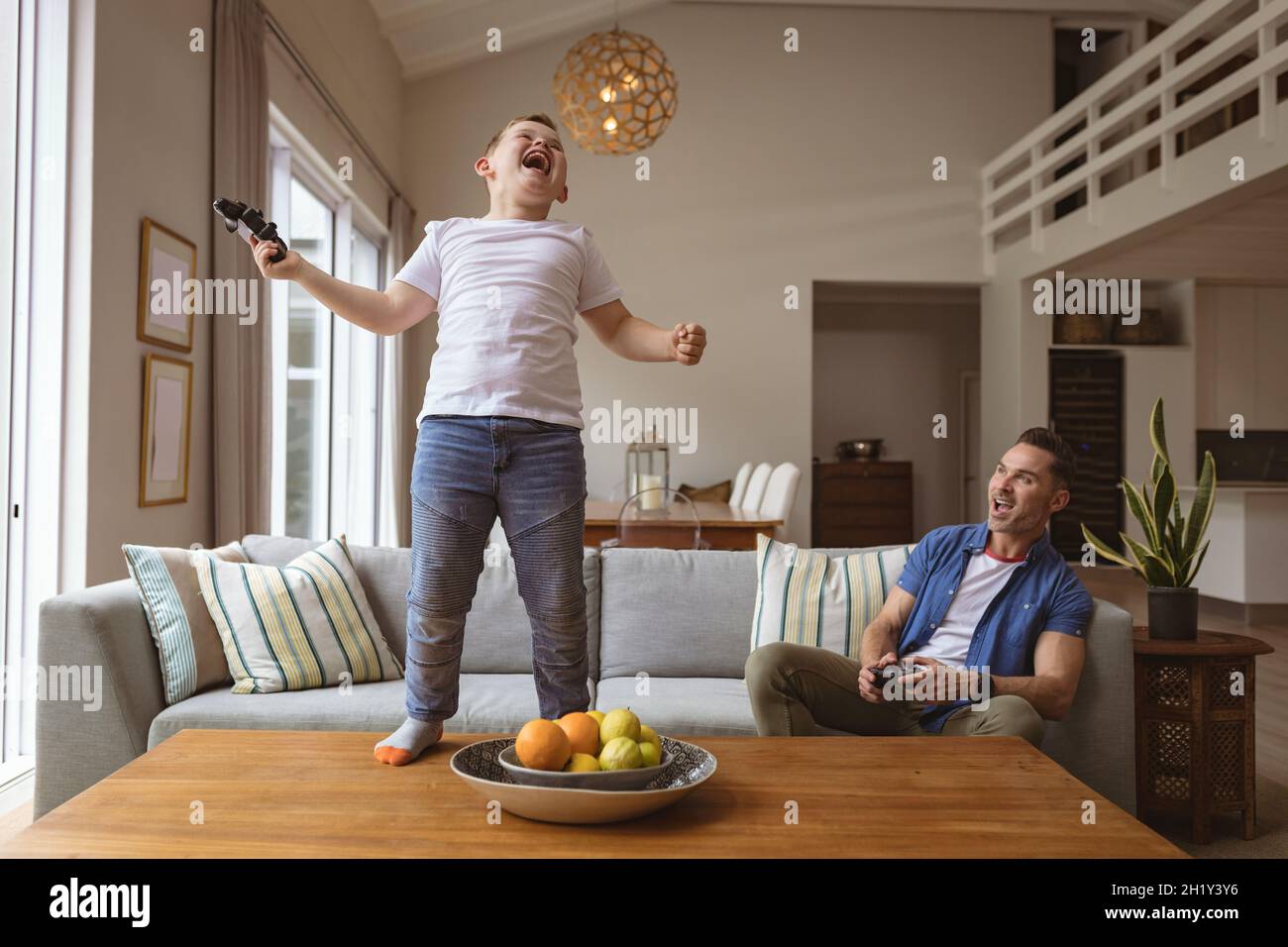 Caucasian boy celebrating standing on the table while playing video