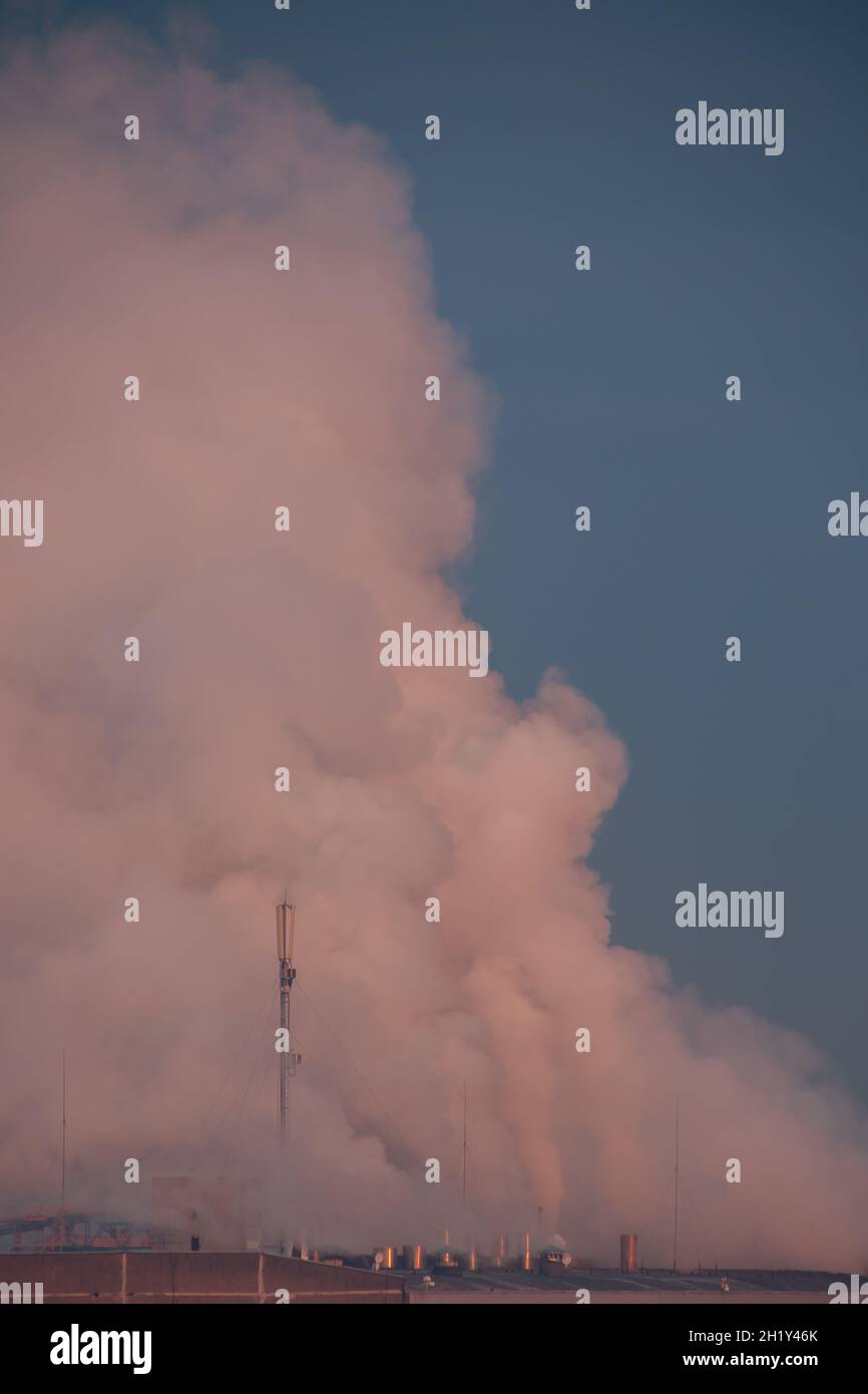 Vertical shot of the smoke coming out from the industrial pipes Stock Photo