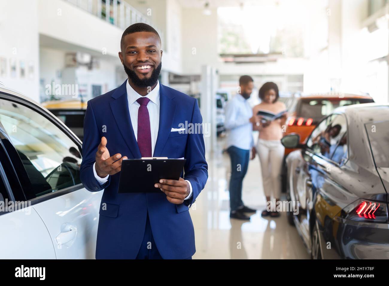 Car Dealership. Handsome Black Manager Posing At Workplace In Auto