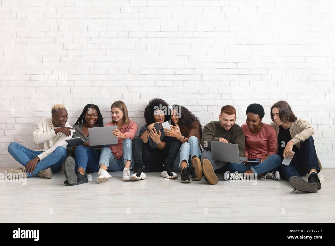 Joyful multiracial friends having fun, using gadgets and chatting Stock Photo