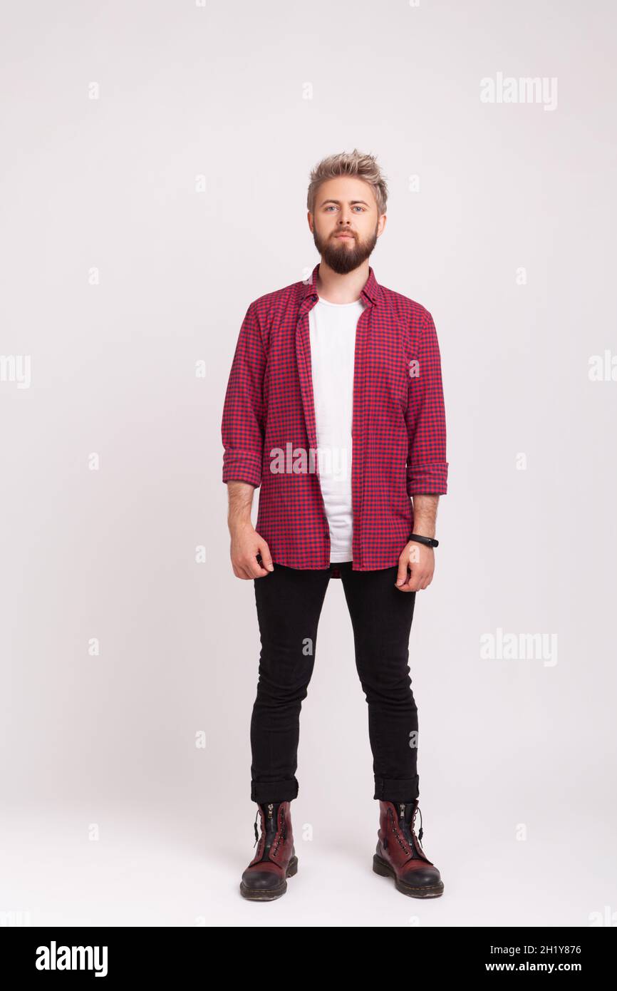 Full length body of serious self-confident man with beard wearing stylish plaid shirt and casual black pants standing straight, looking at camera. Indoor studio shot isolated on gray background Stock Photo