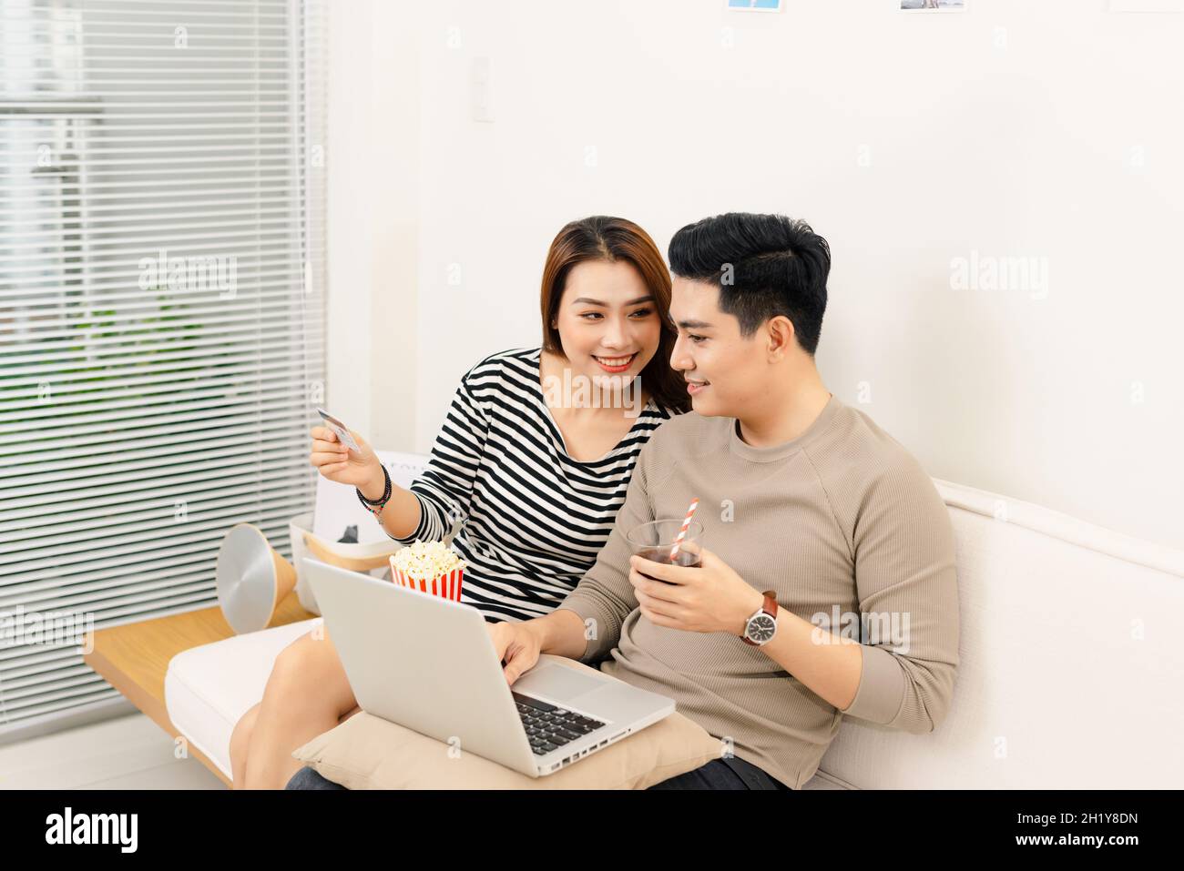 Portrait of young asian couple relaxing and watching a movie with laptop on couch at home. Stock Photo