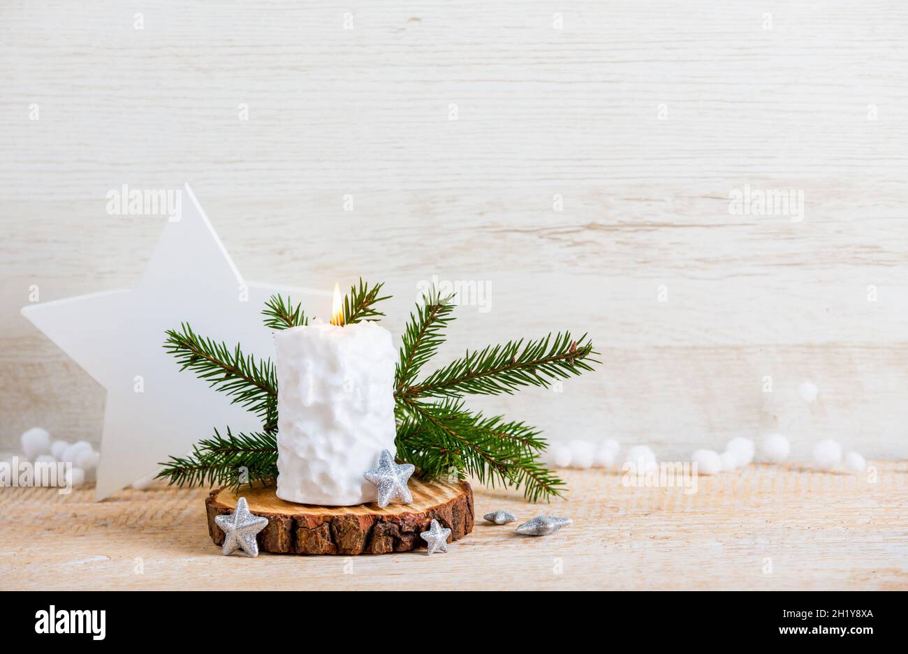 Vintage Nordic style minimalist Christmas background with a lot of copy space. Selective focus on snow ball pattern white candle burning, star shape. Stock Photo
