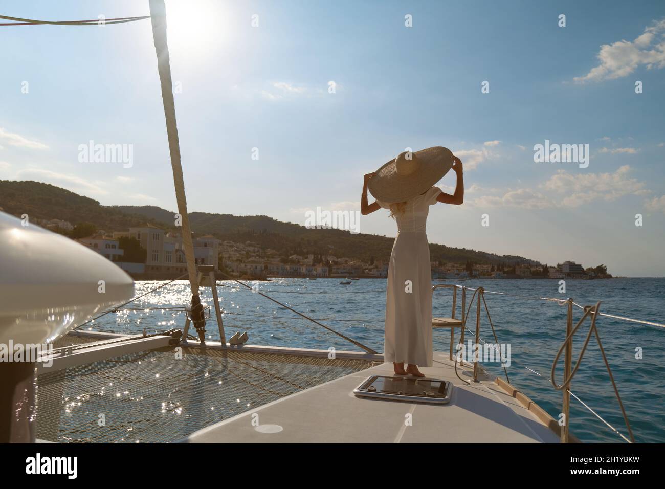 Beautiful woman wearing straw hat and white dress on a yacht enjoys the journey, Spetses, Greece, Europe Stock Photo