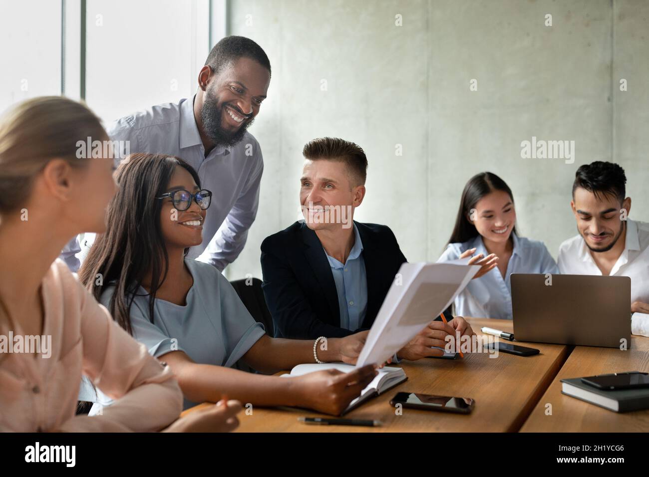 Portrait Of Smiling Young Business People Communicating During Corporate Meeting In Office Stock Photo