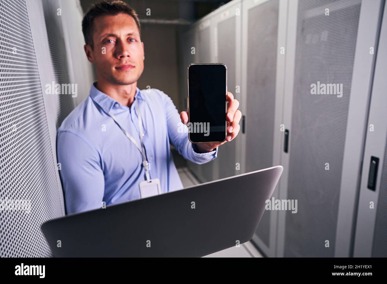 Calm system administrator standing in server room Stock Photo - Alamy