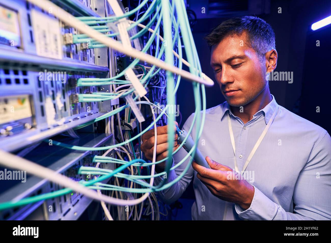 Serious focused IT technician testing cabling performance Stock Photo