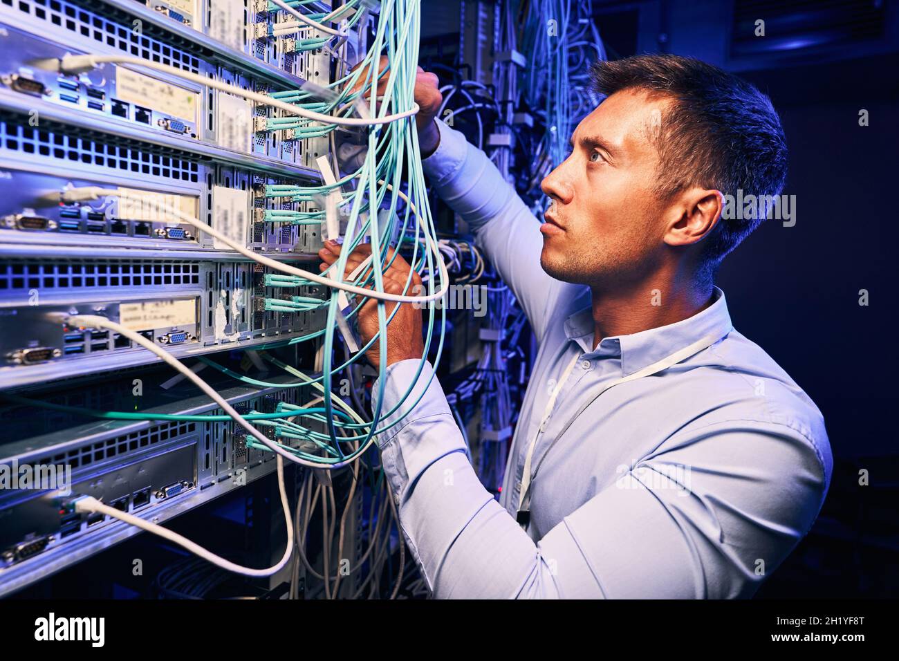 Skilled focused system administrator inspecting fiberl cabling Stock Photo