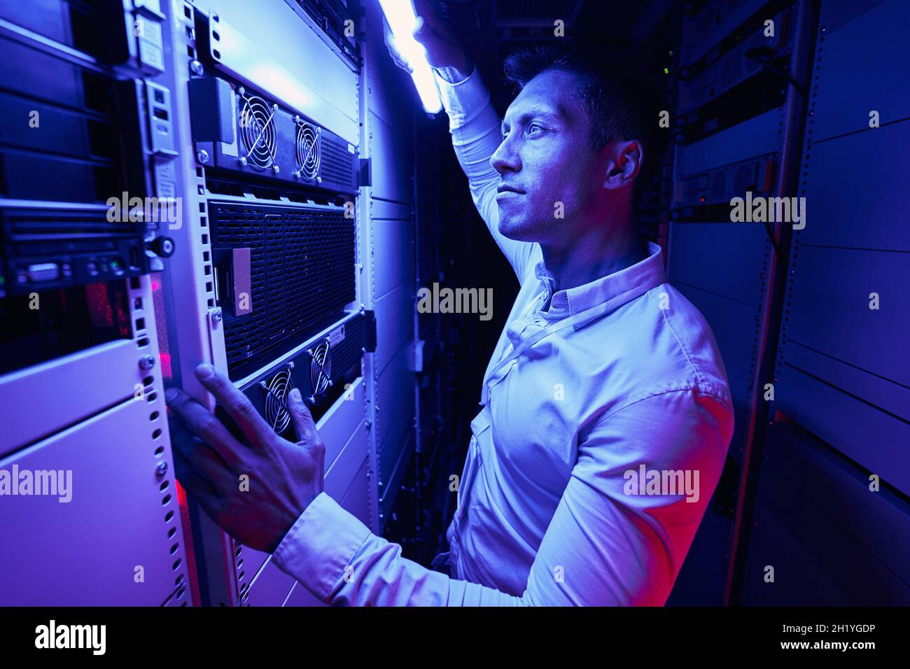 Experienced serious system administrator monitoring network server Stock Photo