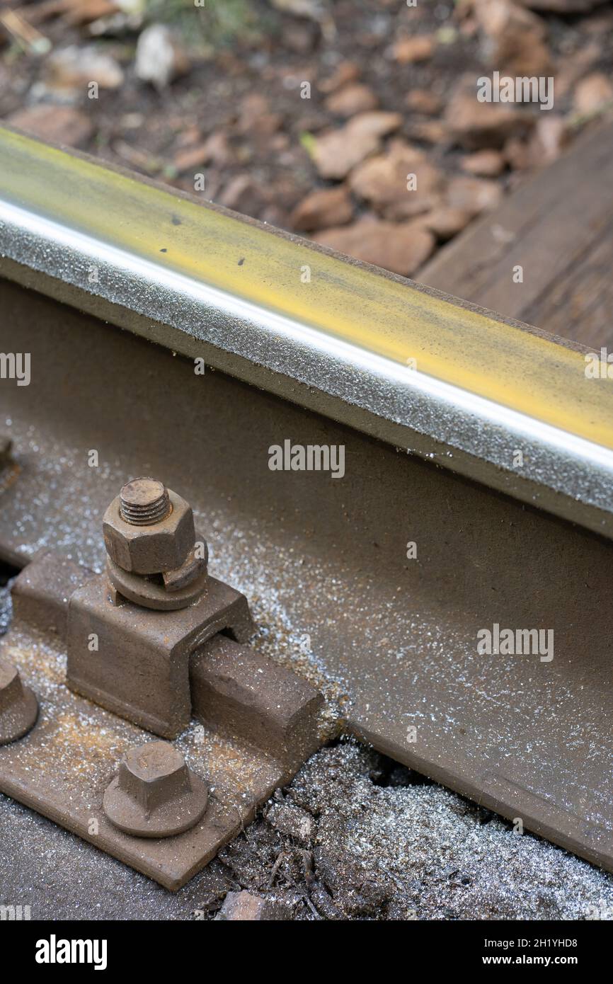 Closeup of increased lateral wear of steel rail with metal shavings in a very steep curve.  Stock Photo