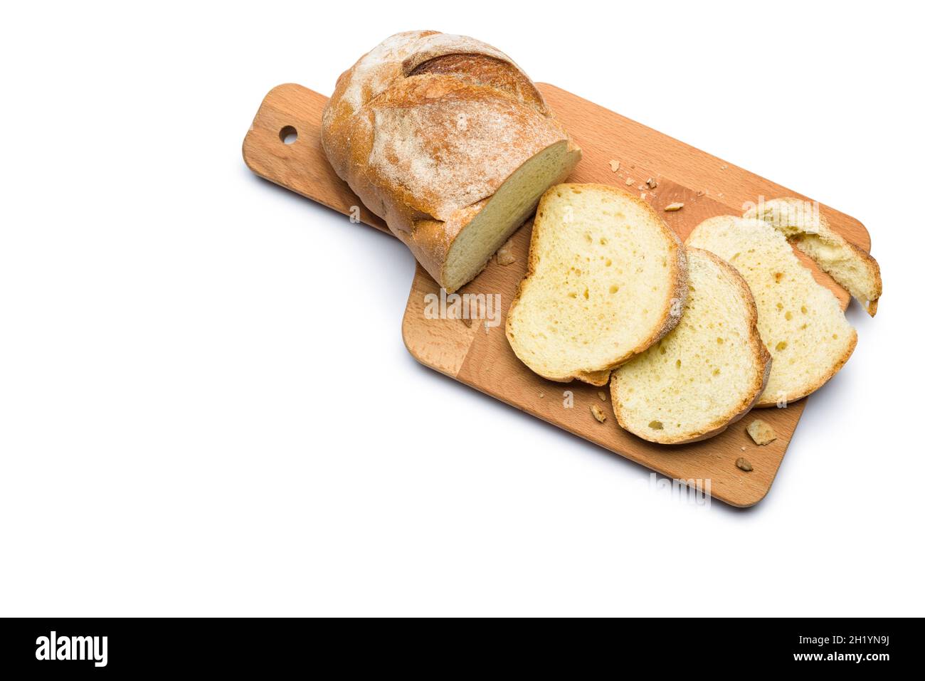 Sliced fresh bread and crumbs on wooden cutting board. Top view isolated on white background. Stock Photo