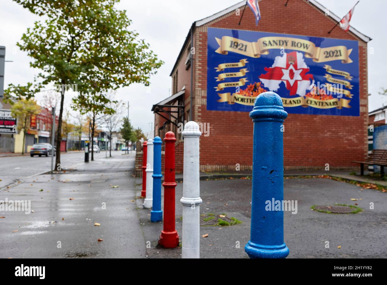 red white and blue painted posts and northern ireland centenary mural sandy row belfast northern ireland Stock Photo