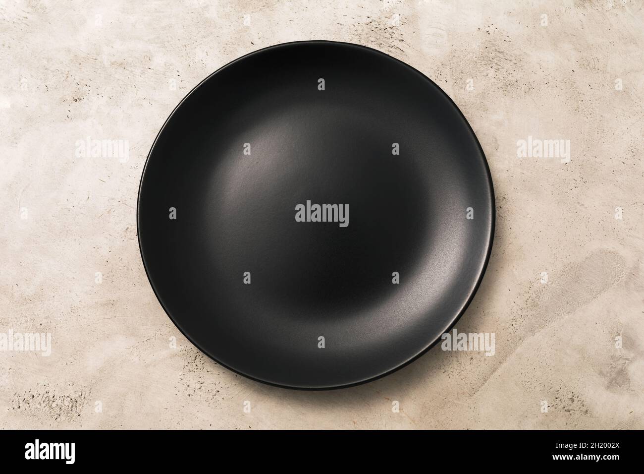 Empty black ceramic plate on light abstract background, top view, food background Stock Photo
