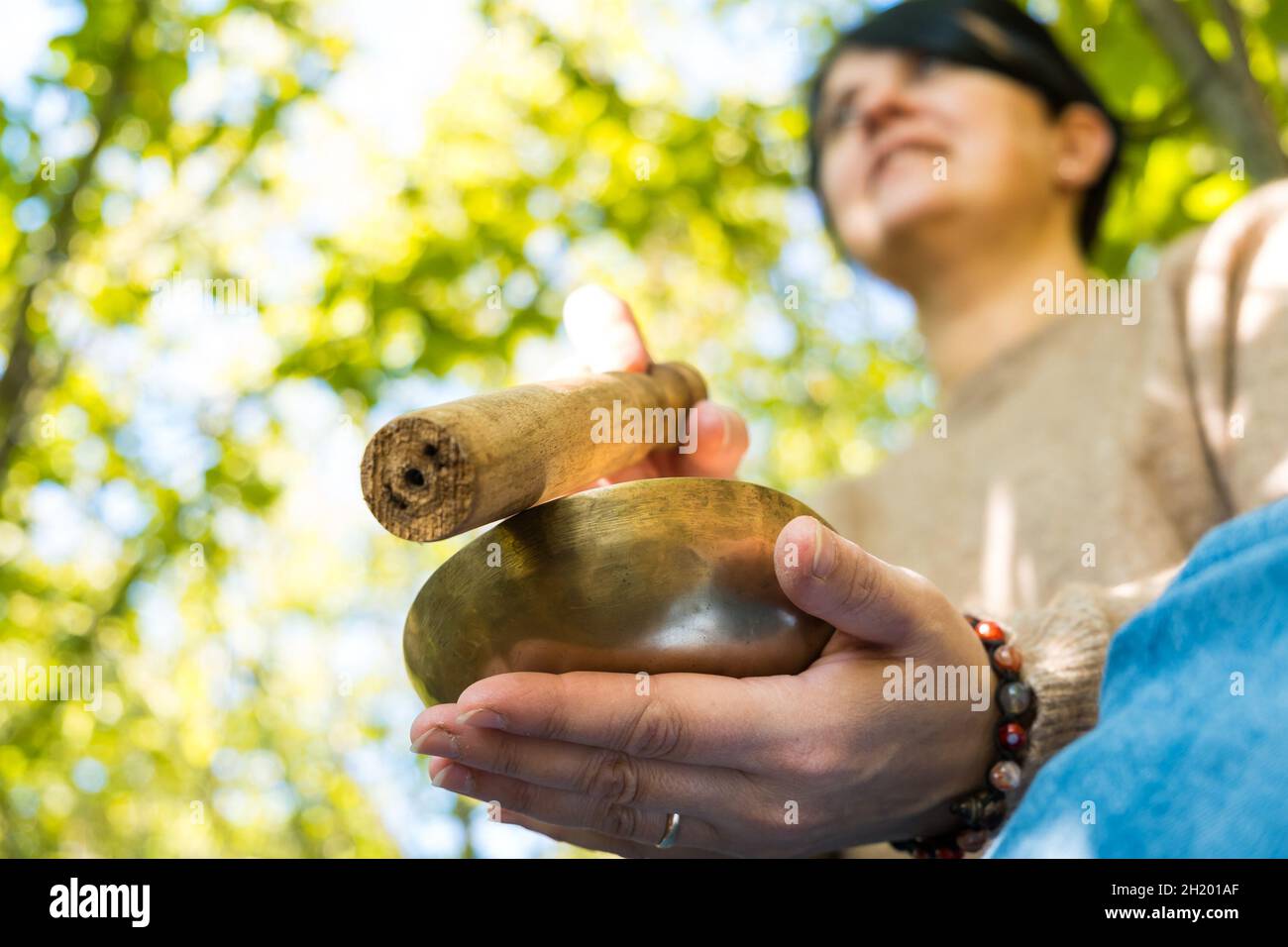 Woman playing on a tibetian singing bowl for sound therapy in atmosphere for meditation and relax. Healing sound. Stock Photo