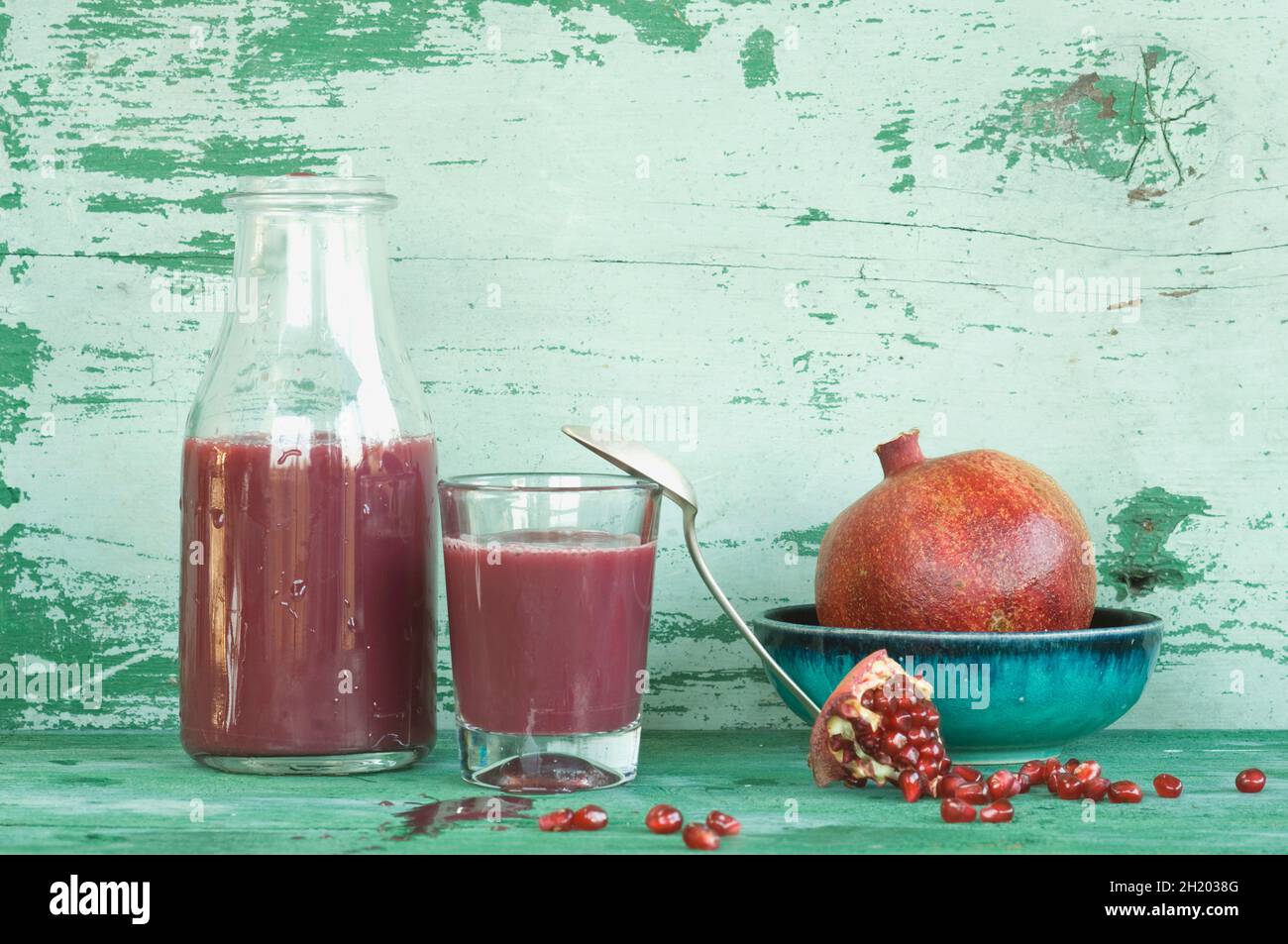 An arrangement of pomegranates and pomegranate juice in a bottle and a