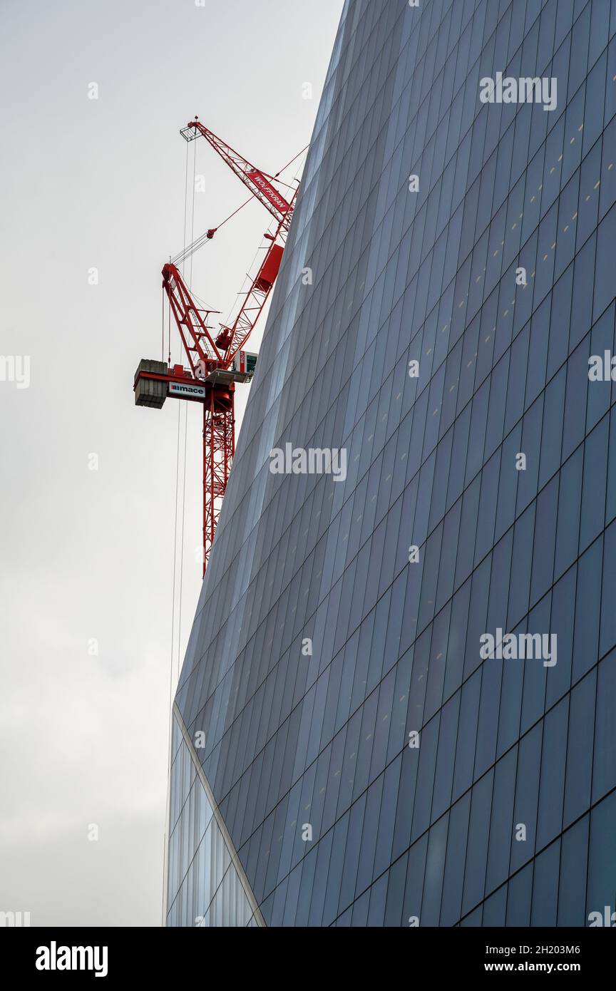 The Scalpel building glass facade at 52 Lime Street seen from the side with parts of construction cranes visible next to it. City of London, England. Stock Photo