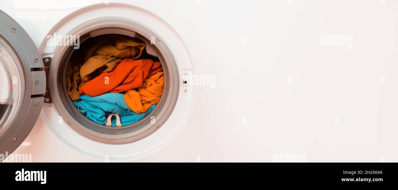 Bright clothes inside washing machine. Stock Photo