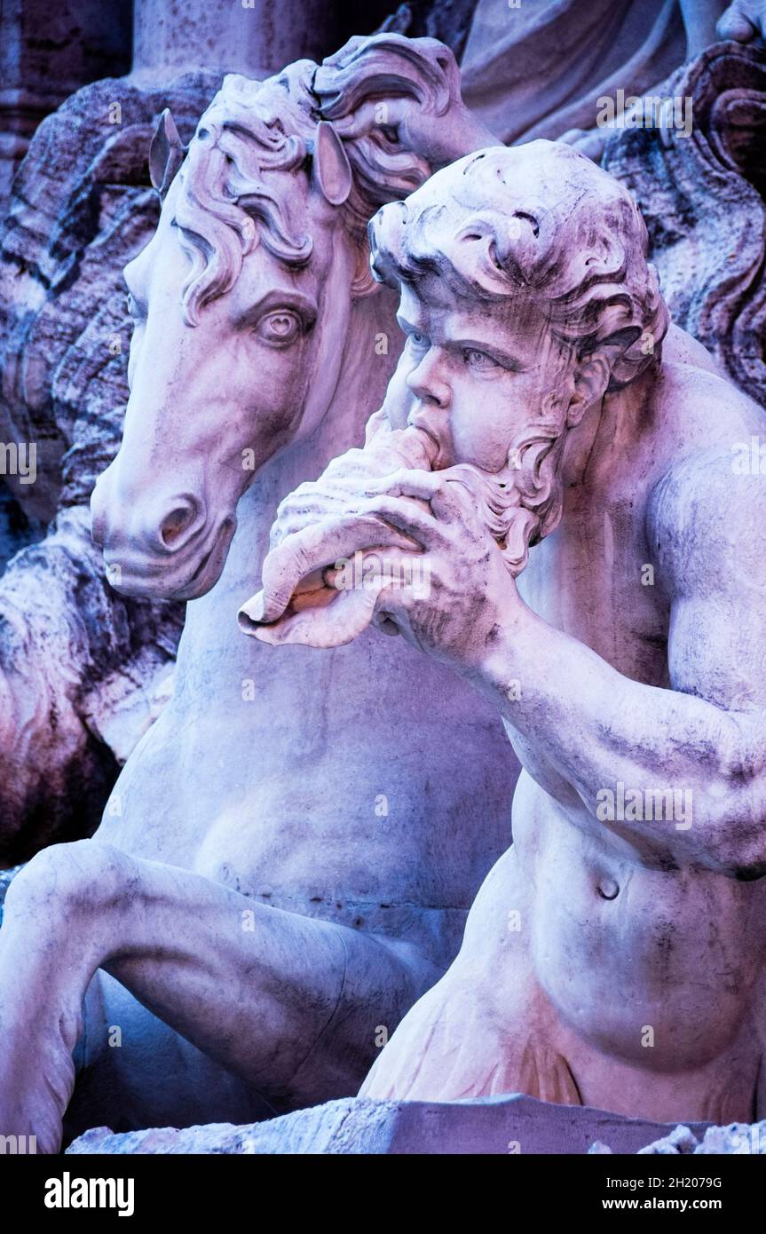Triton is Greek God of the Sea depicted as having a conch shell he would blow like a trumpte at the Baroque Trevi Fountain in Rome, Italy. Stock Photo
