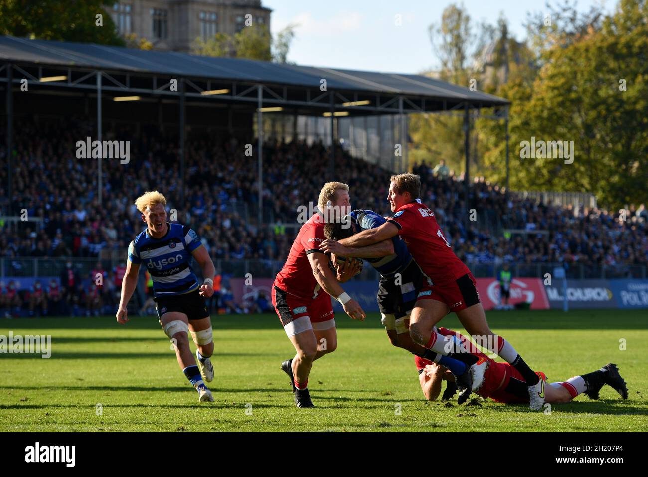 The Recreation Ground, Bath, England, UK. 17th October, 2021. Bath Rugby's Josh Bayliss is tackled by Saracens' Vincent Koch (left) and Max Malins during the Gallagher English Premiership match between Bath Rugby and Saracens: Credit: Ashley Western/Alamy Live News Stock Photo