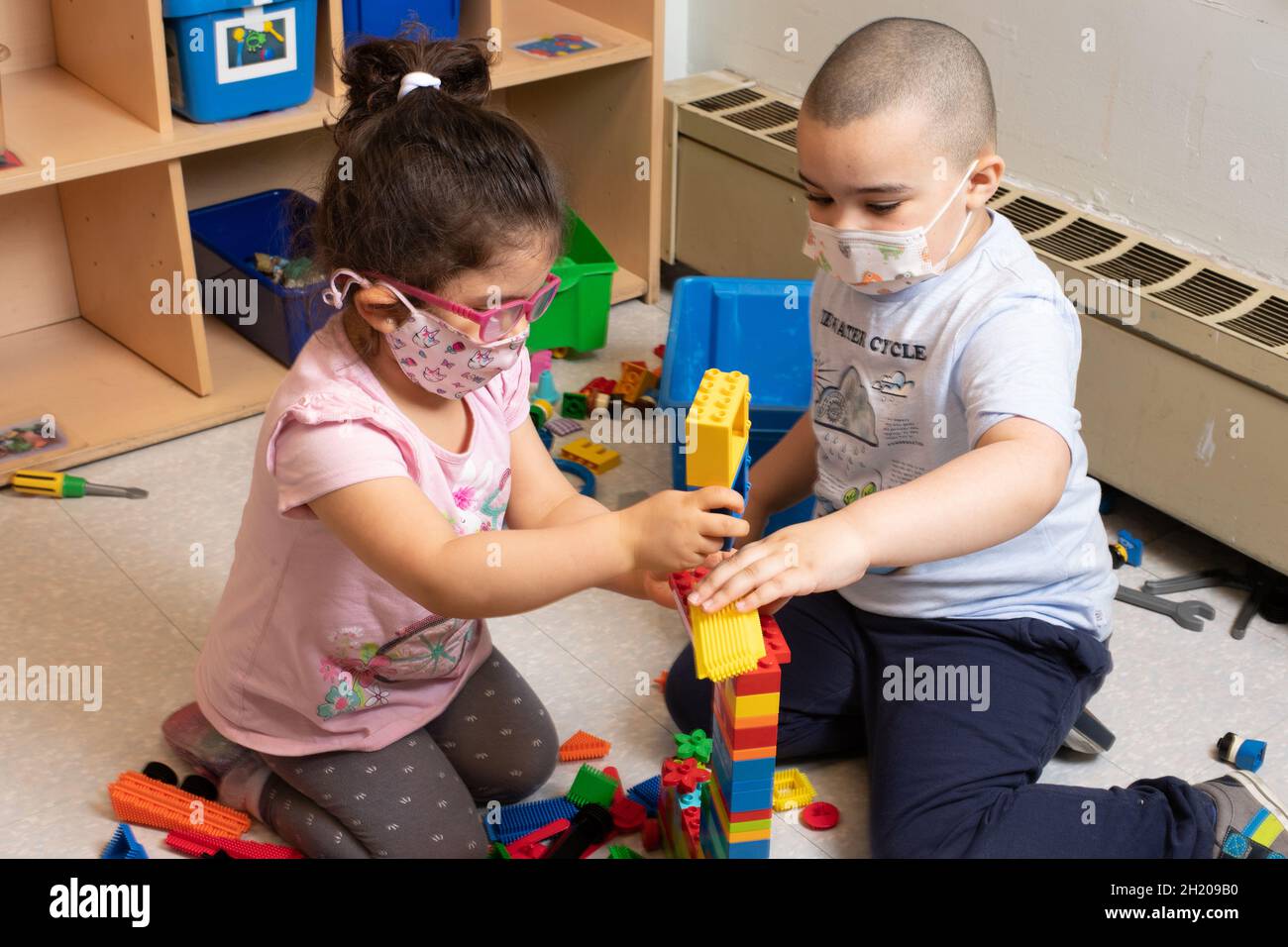 Education Preschool 3-4 year olds boy and girl playing together building with colorful plastic bricks (Duplo) Stock Photo