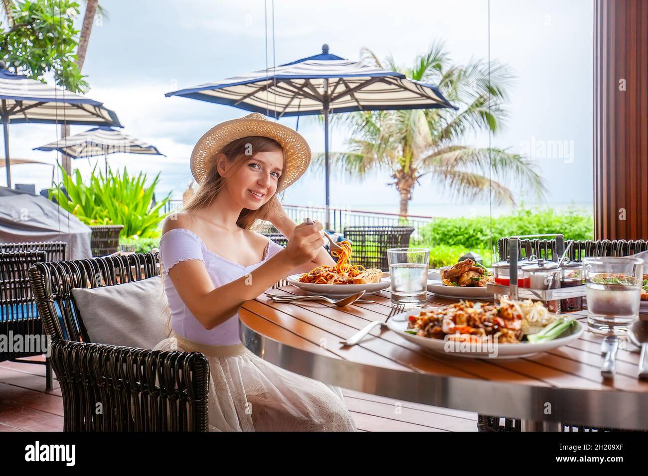 Attractive woman eats italian pasta in outdoor restaurant or cafe, prepared food Stock Photo