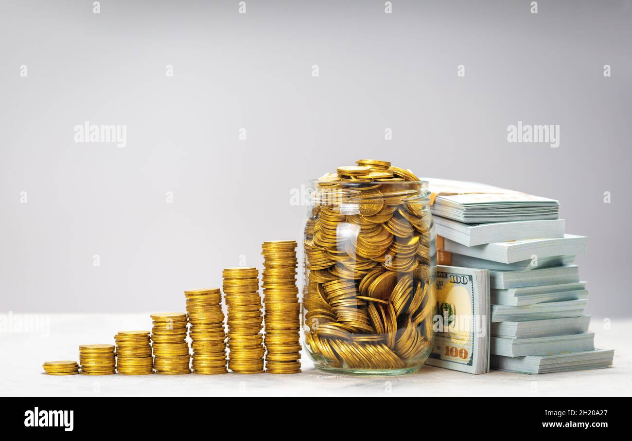 Savings growth or successful investment. Pile of gold coins with steps and glass jar full of coins. Stacks of dollars banknotes. Template Copy space for text. Stock Photo