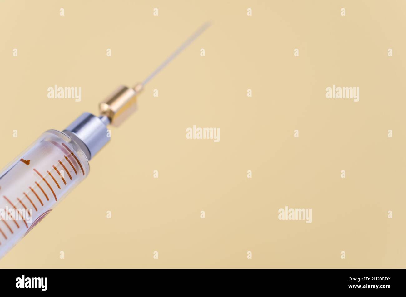 isolated sterilized glass injection syringe on a yellow paper
