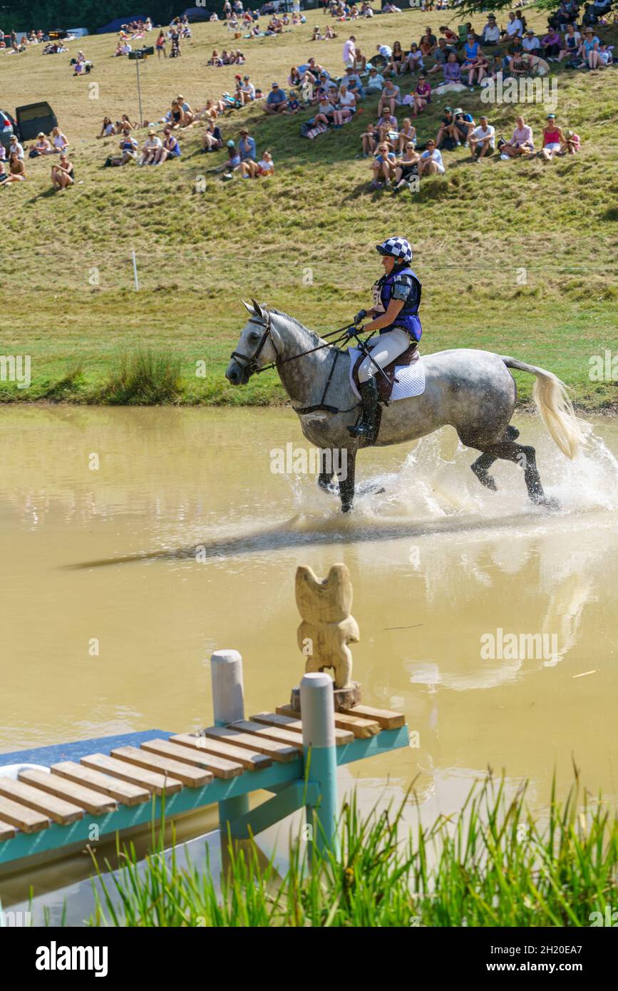 Horse and rider takling the cross country course and water jumps at an eventing competition in Gloucestershire, UK, in 2018. Stock Photo