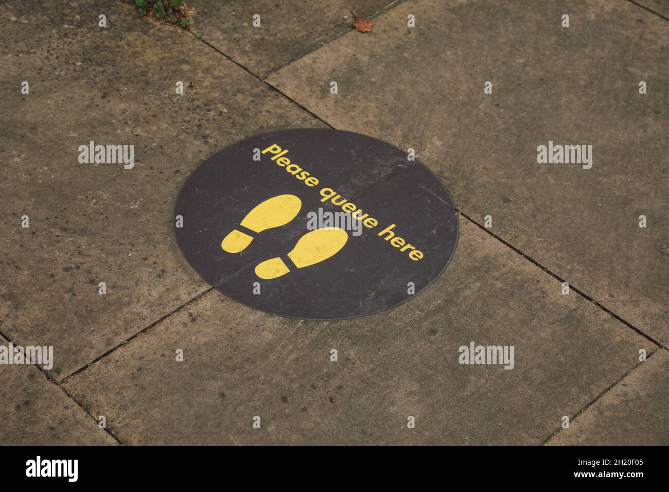 'Please queue here' 2-metre social distancing markers on the ground during Covid-19 pandemic Stock Photo