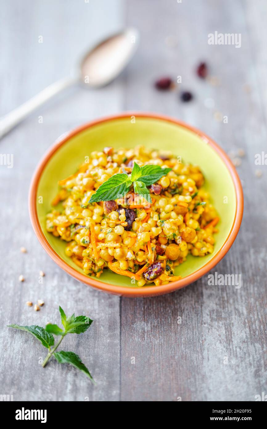 A salad with pearl couscous, chickpeas, carrots, curry cream and cranberries Stock Photo