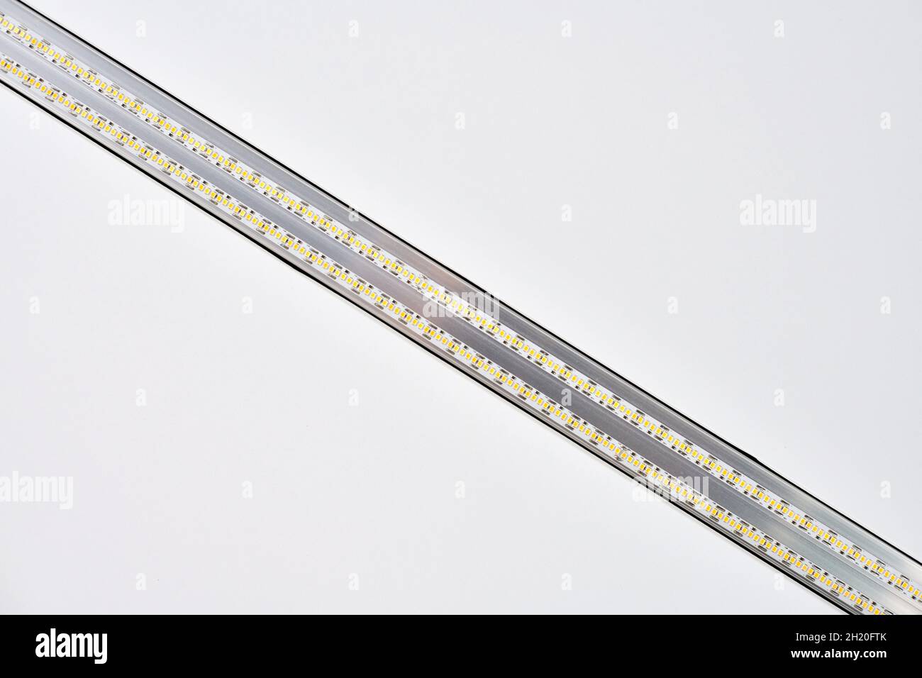 Strip LED light with aluminum profile on white stretch ceiling in house
