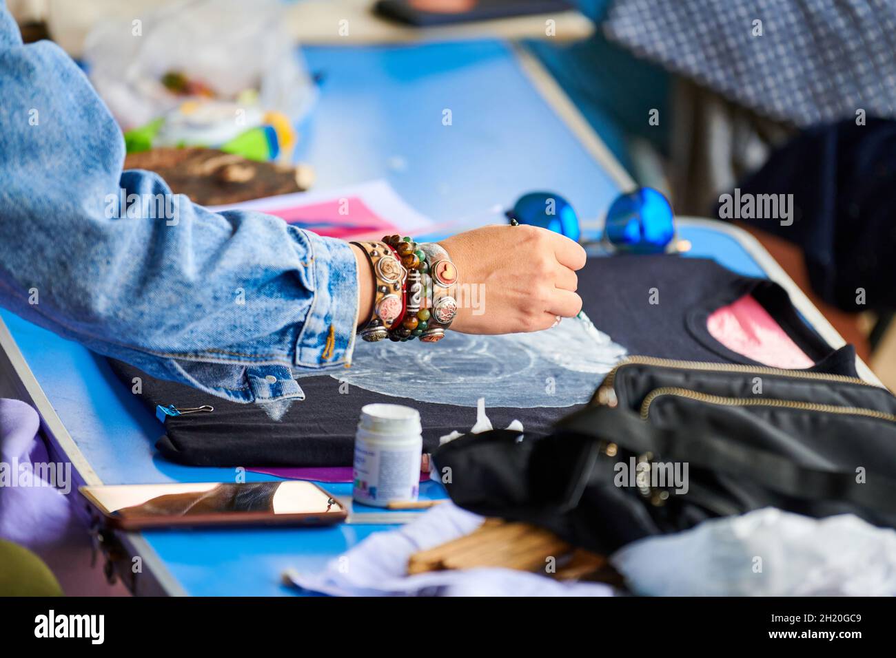 Female artist hand painting on black Tshirt using brush and fabric