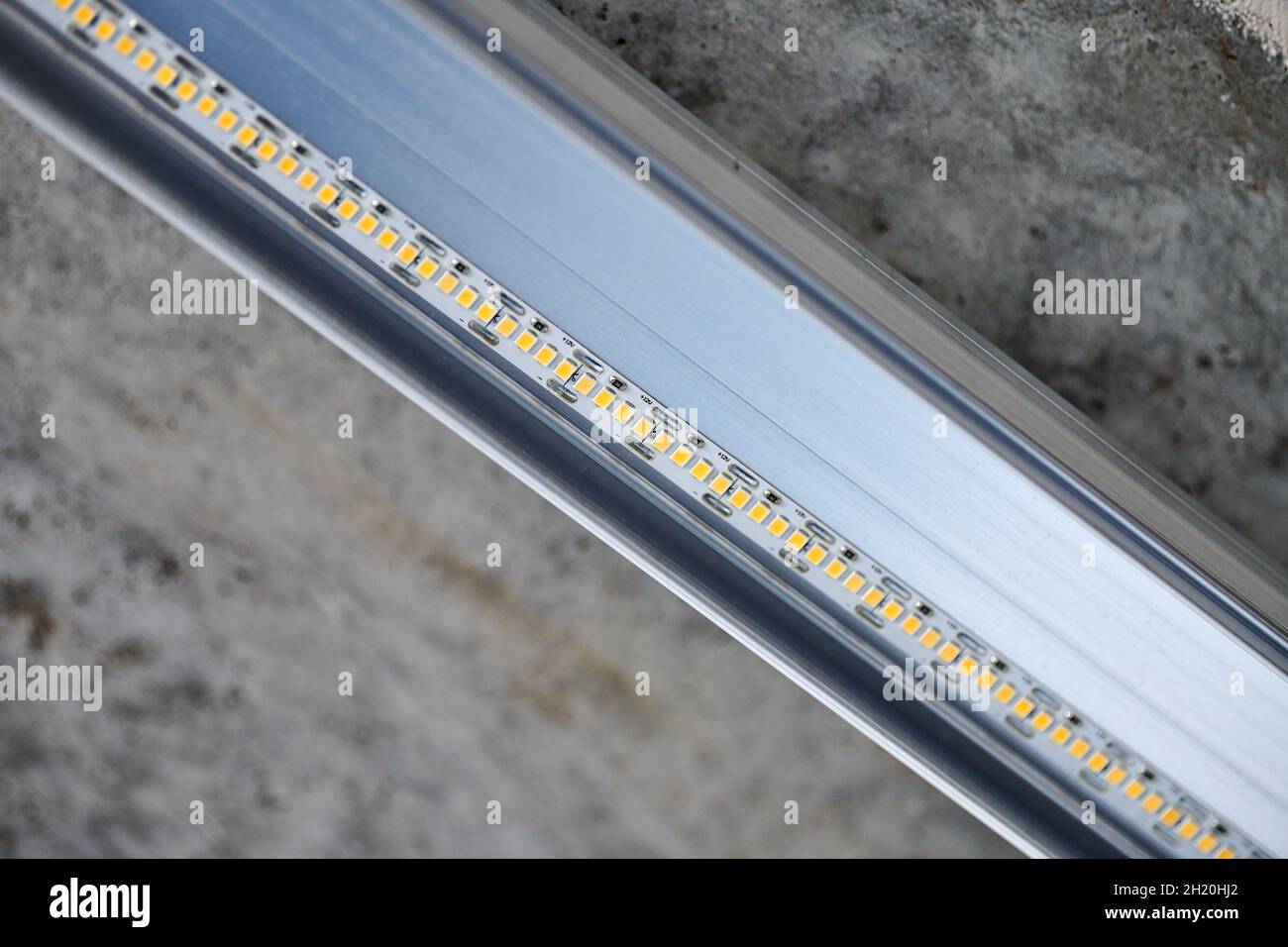 LED strip with aluminum profile on rough wall. Concrete ceiling with LED lighting in residential building, indoor photo, close up. Home renovation con Stock Photo