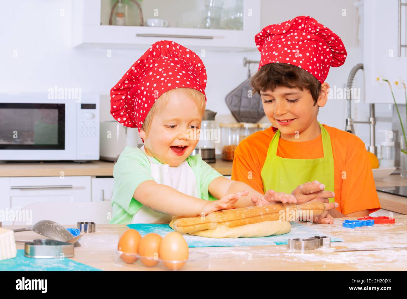 Two boys cook and bake cookies wearing chef hat Stock Photo - Alamy