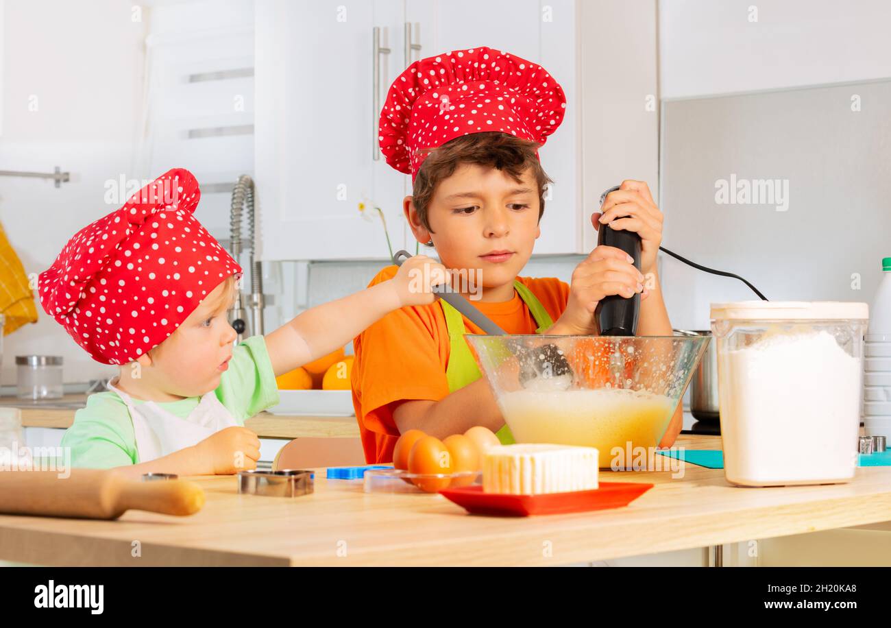 Two happy boys mix dough in bowl preparing cookie Stock Photo