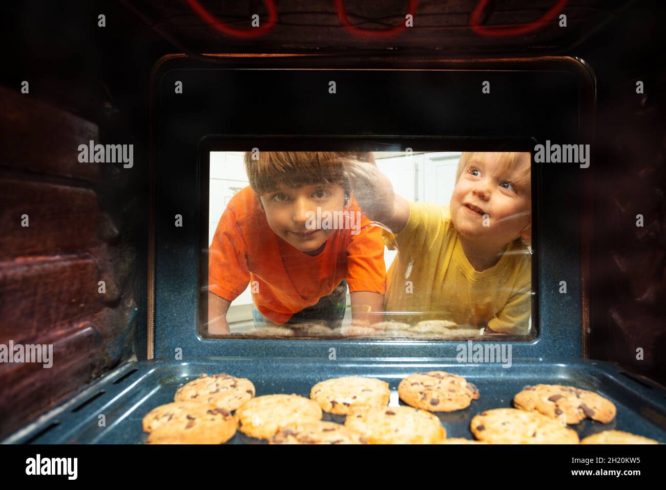 Boys brothers look though oven glass at cookies Stock Photo