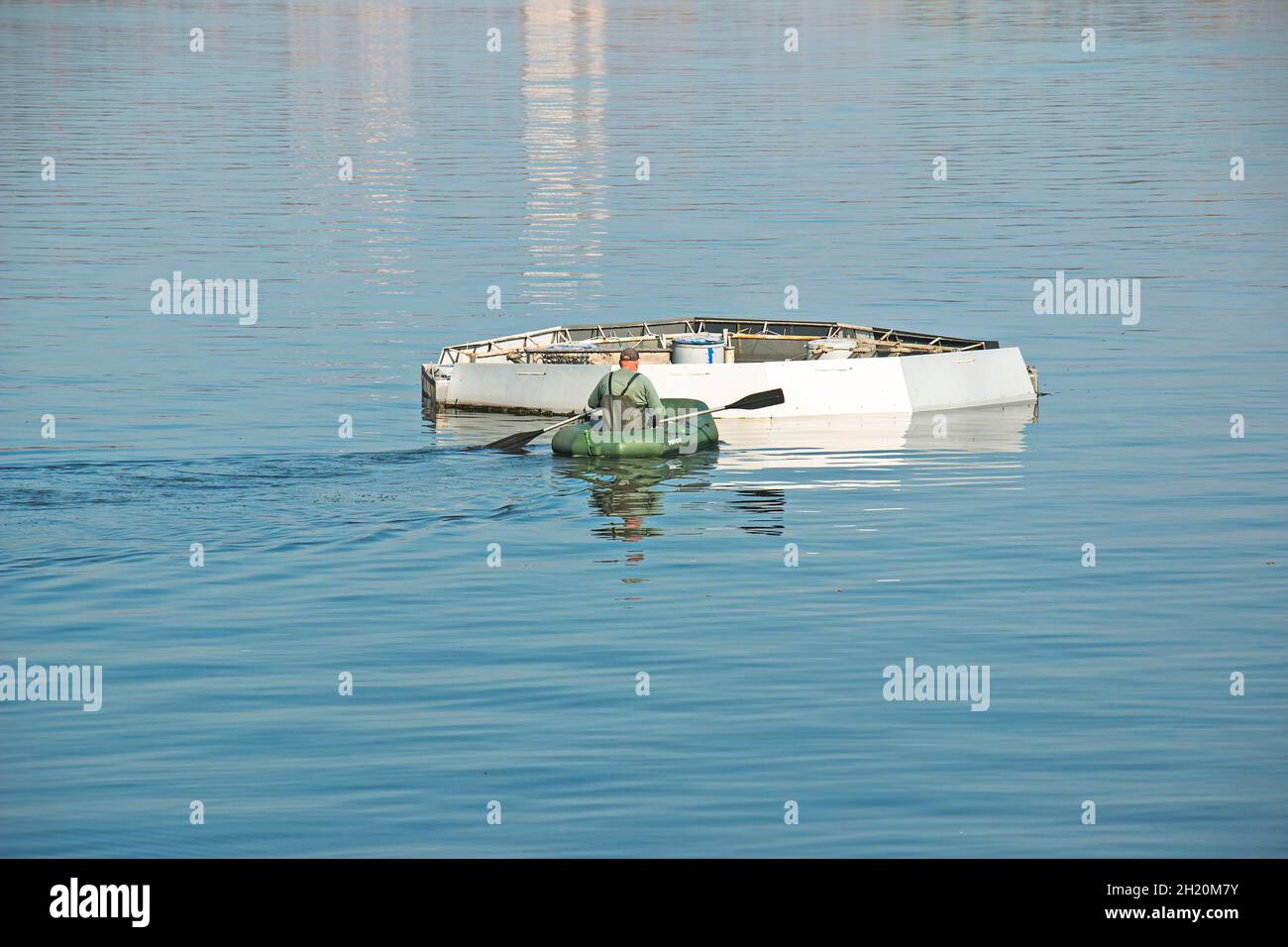 Dnepropetrovsk, Ukraine - 10.15.2021: Maintenance works of the city fountain. A municipal service worker delivers a tool for working on a rubber boat. Stock Photo