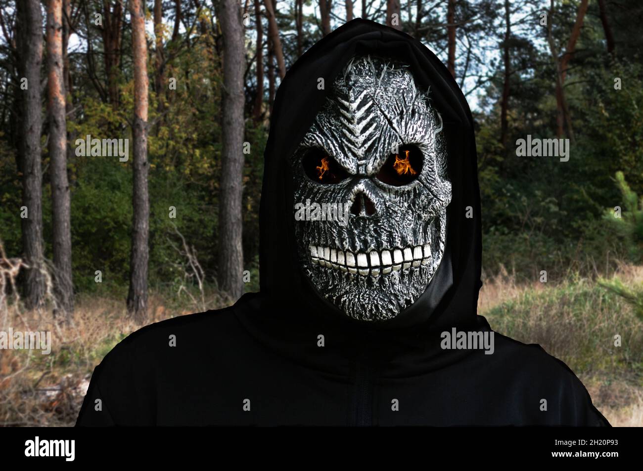 Close-up portrait of grim reaper. Man in death mask with fire fl Stock Photo