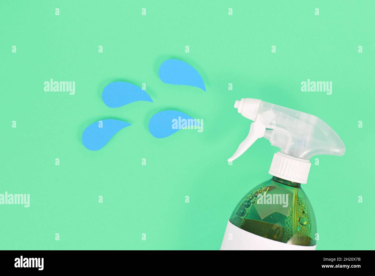 Green cleaning agent spray bottle with blue liquid drops cut from paper Stock Photo