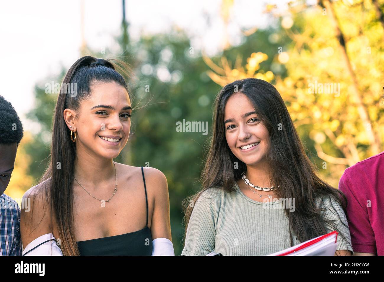 Two young woman facing the camera while standing in a park Stock Photo
