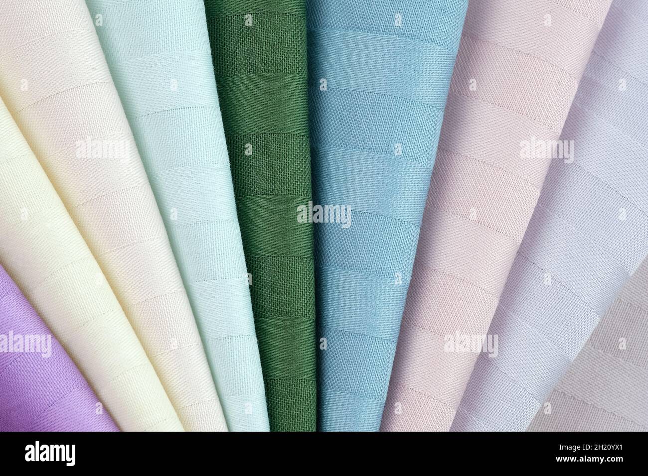 Bed linen fabric samples. Beautiful high-quality fabric for sewing bed linen. Samples of color stripe satin background. Cotton textiles of white, gree Stock Photo